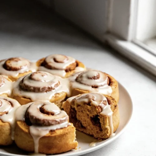 Freshly baked pumpkin cinnamon rolls with cream icing on top